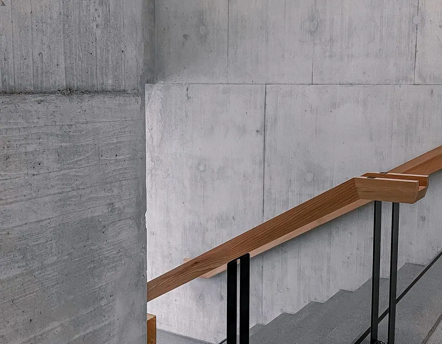Sichtbetonwand mit Holzhandlauf in einem modernen Gebäude