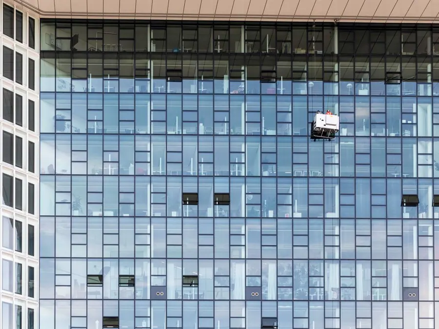Glasfassade eines Hochhauses mit Fensterreinigern in der Höhe
